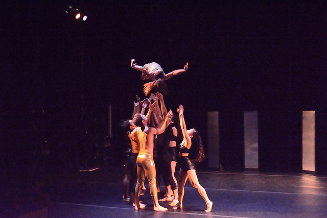 Dancers throwing another dancer into the air.